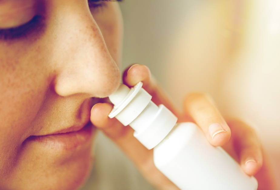 Жена си пръска спрей за нос в носа