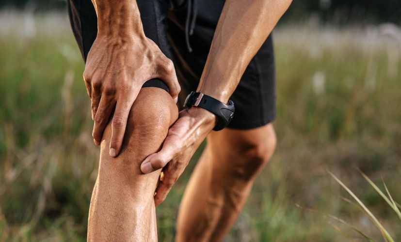 man-holding-injured-knee-in-a-grassy-field