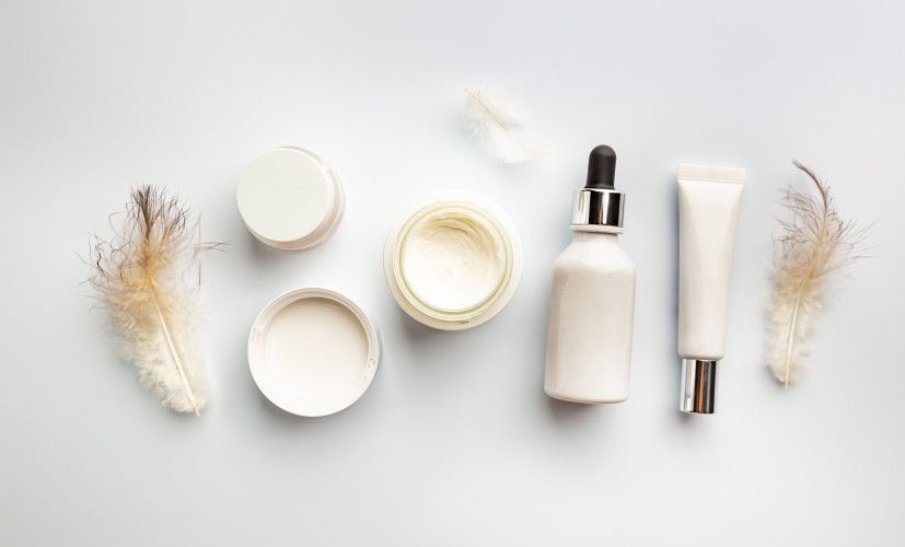 skin-care-products-and-feathers-on-white-background