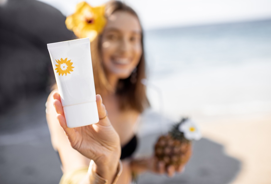 Жена със слънцезащитен крем на плажа